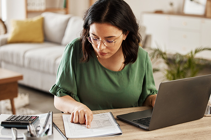 A woman sits at her desk to create a budget.