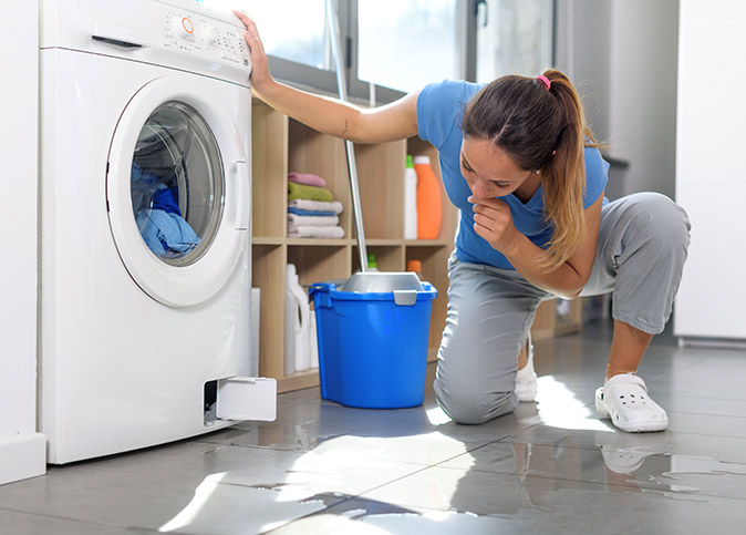 A woman checking her washer water leak.