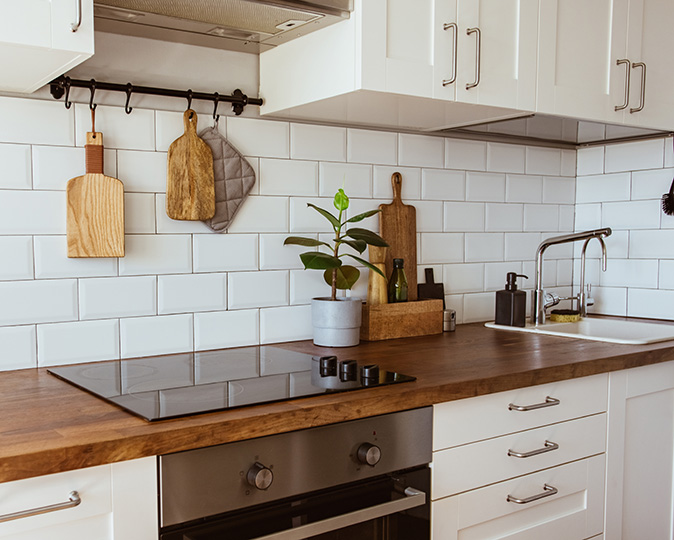 White farmhouse kitchen with thick wood countertop and white backsplash tiles.