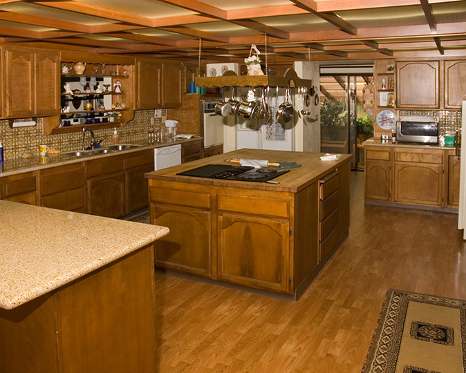 A large kitchen with a pot and pan rack hanging over a kitchen island.