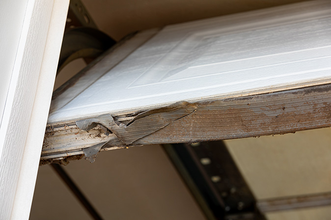 Dirty and worn-out weatherstripping on a garage door.