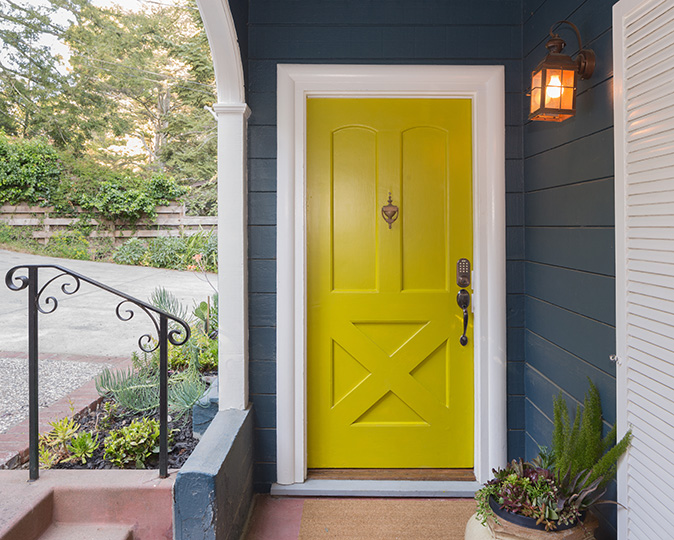 A bright yellow-green front door on a dark gray home.